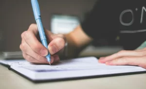 Foto orang menulis di buku