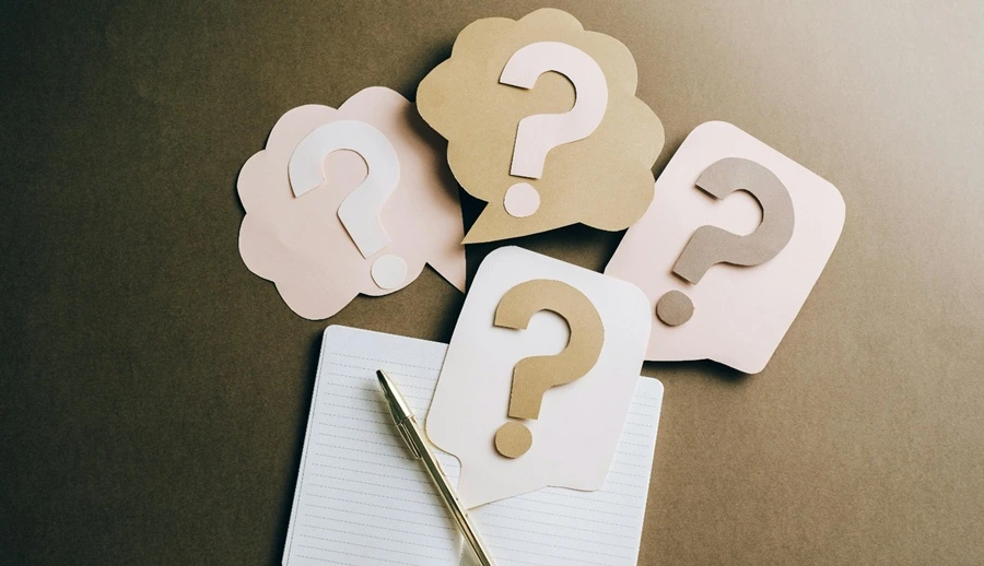 Empat simbol tanda tanya disertai sebuah buku dan pulpen di bawahnya